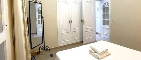 Un dormitorio con cama, armario y espejo.