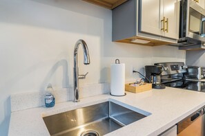 Eine moderne Küche mit Spüle aus Edelstahl, einer Kaffeemaschine und einer Holzkiste auf der Arbeitsplatte.