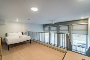 A hotel room with a bed, a ceiling fan, and a view of the street through large windows. - Urban Loft Escape -  Nearby Parking Downtown - 2F (Louisville)
