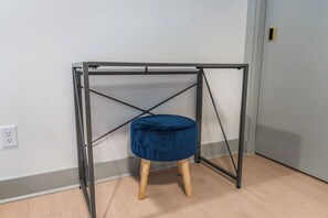 Une table à ossature métallique, avec un tabouret bleu rembourré placé en dessous.