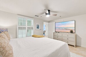 Ein Schlafzimmer mit Bett, Fernseher, Schminktisch und Meerblick durch das Fenster.