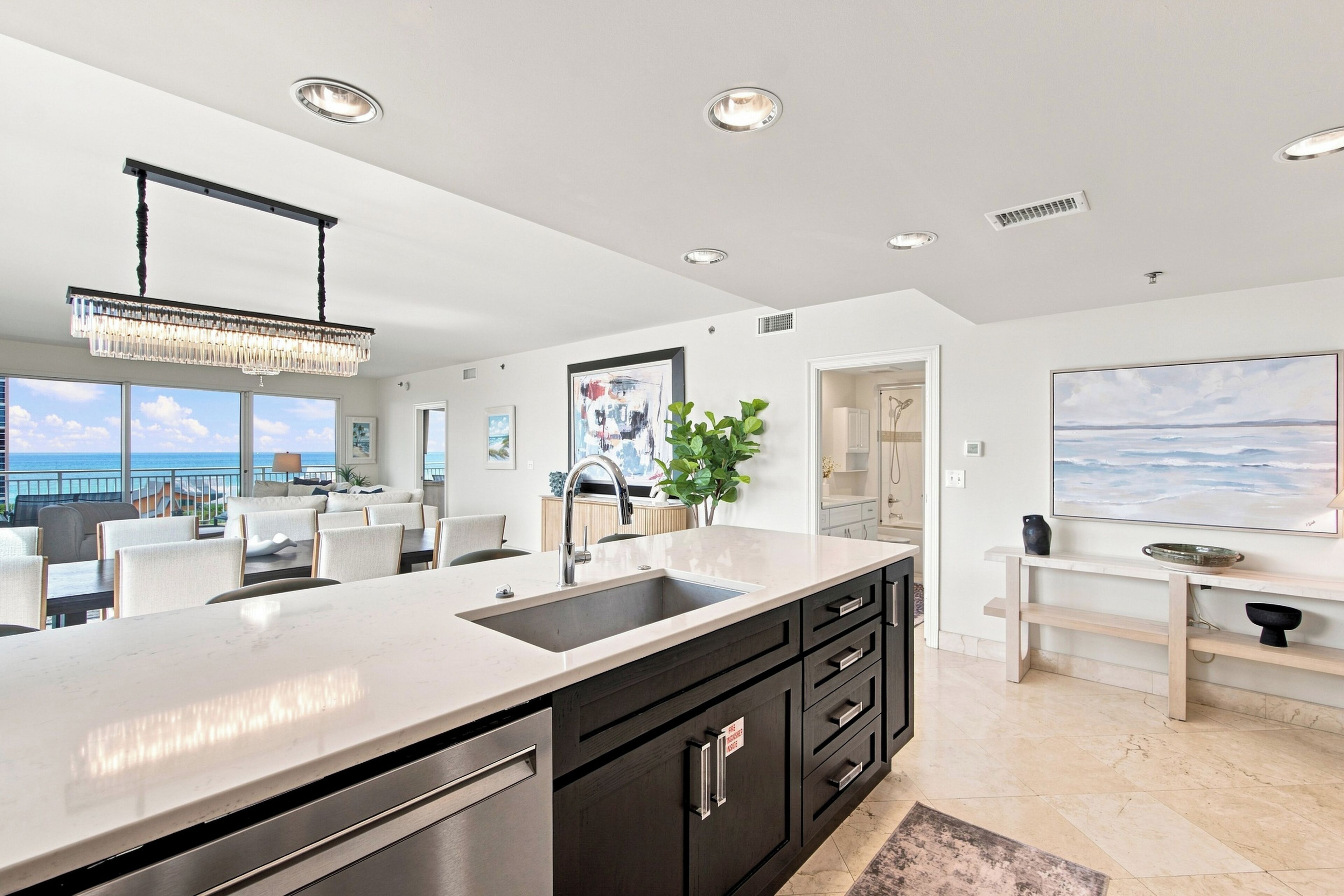 A modern kitchen with a large island, stainless steel appliances, and a view of the ocean.