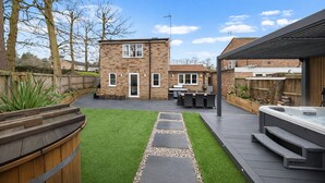Un jardin avec une terrasse, un espace barbecue et un jacuzzi.