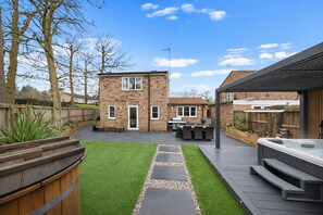 Ein Garten mit Terrasse, Grillplatz und Whirlpool.