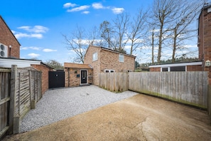 A residential property with a gravel driveway, a wooden fence, and a brick house with a tiled roof. - Luxury Countryside Retreat with HotTub (Mildenhall)
