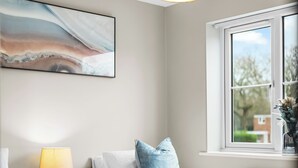 Une chambre avec deux lits, une table de chevet avec une lampe, une fenêtre donnant sur un beau paysage et un tableau accroché au mur.