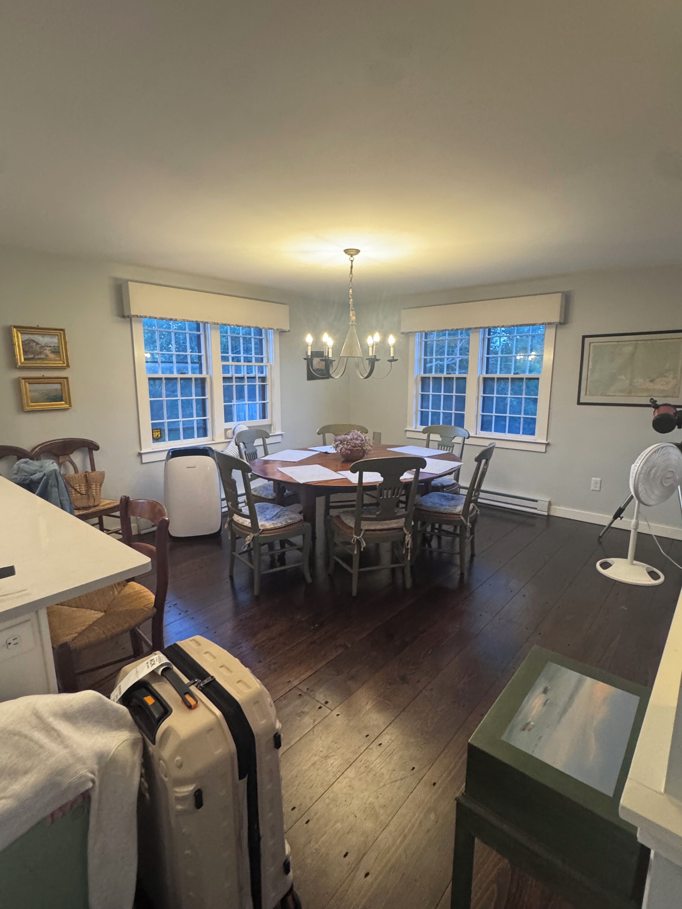 A dining area with a table and chairs, a chandelier, and large windows.