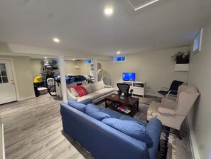Ein Wohnzimmer mit einer Couch, einem Couchtisch, einem Fernseher und einem Sessel.