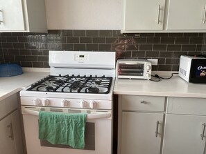 A kitchen with a gas stove, a toaster, and a white refrigerator. - Cozy 2-bedroom apartment in serene Brighton with AC (Bridgetown)