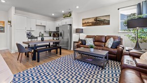 A modern kitchen with white cabinets, stainless steel appliances, and a dining area with a wooden table and chairs.