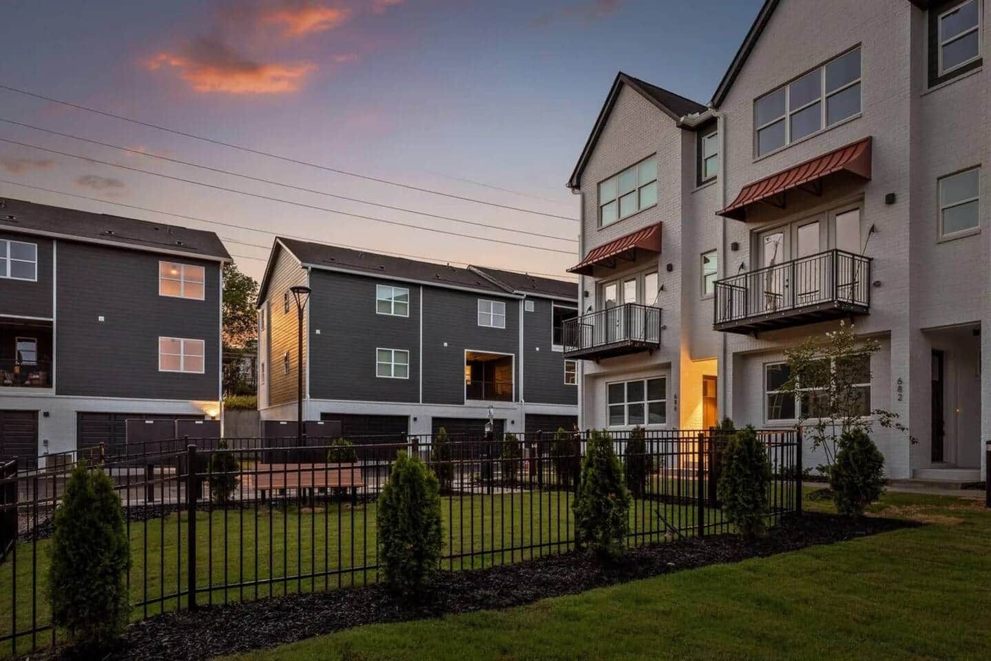 A residential building with multiple floors, balconies, and a fenced courtyard.