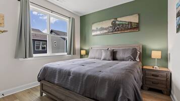 A bedroom with a large bed, a nightstand, a lamp, and a painting on the wall.