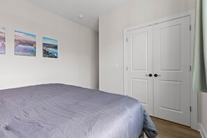 A bedroom with a bed, two doors, and two landscape paintings on the wall. - ChattVistas|Dwntwn Townhouse|Deck Fire Pit|2Bdrm (Chattanooga)