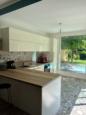 A modern kitchen with a central island, a coffee maker, and a pink mixer. - Villa in Saint-Florent with a pool, 5 minutes from the beach (by car) (Oletta)