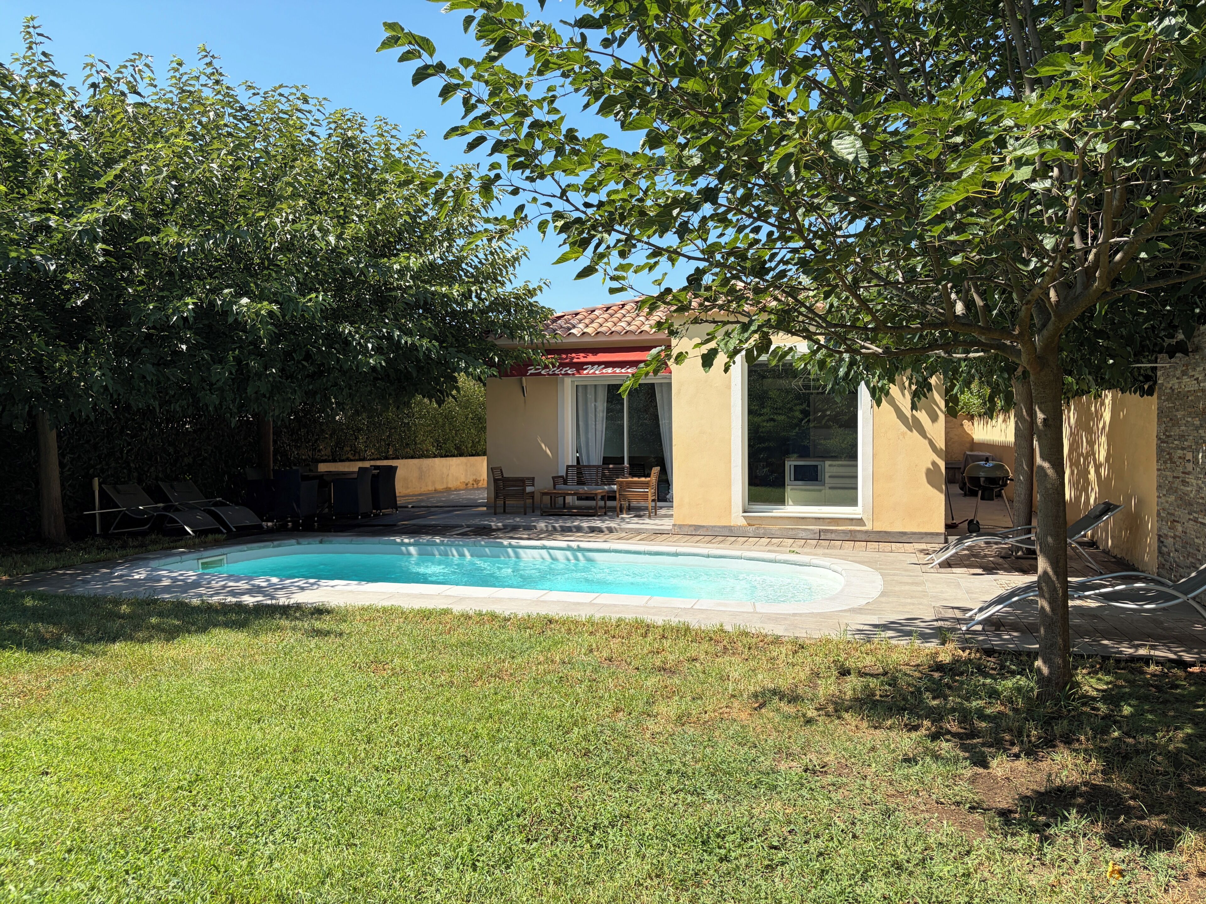 A swimming pool with lounge chairs, a patio area, and a building with a red roof.