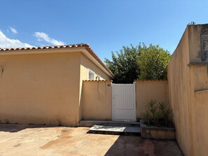 A residential building with a gated entrance, a small garden area with plants, and a clear blue sky. - Villa in Saint-Florent with a pool, 5 minutes from the beach (by car) (Oletta)