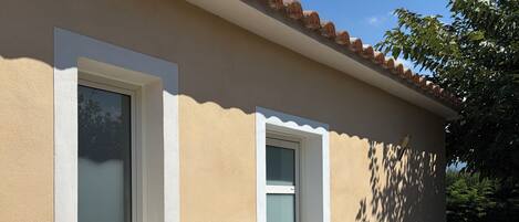 A building with a beige exterior, a window with a white frame, and a door with a white frame.