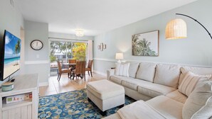 A living room with a sofa, a coffee table, a TV, and a dining area with chairs and a table. - The Salt House 2 BR / 1.5 BA Canal Front Home by RVA (Longboat Key)