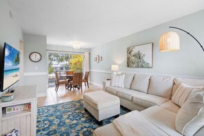 Ein Wohnzimmer mit einer Couch, einem Couchtisch, einem Fernseher und einem Essbereich mit Stühlen und einem Tisch.