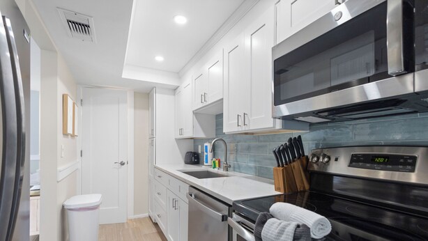 A modern kitchen with stainless steel appliances, white cabinetry, and a built-in oven. - The Salt House 2 BR / 1.5 BA Canal Front Home by RVA (Longboat Key)