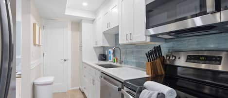 A modern kitchen with stainless steel appliances, white cabinetry, and a built-in oven.