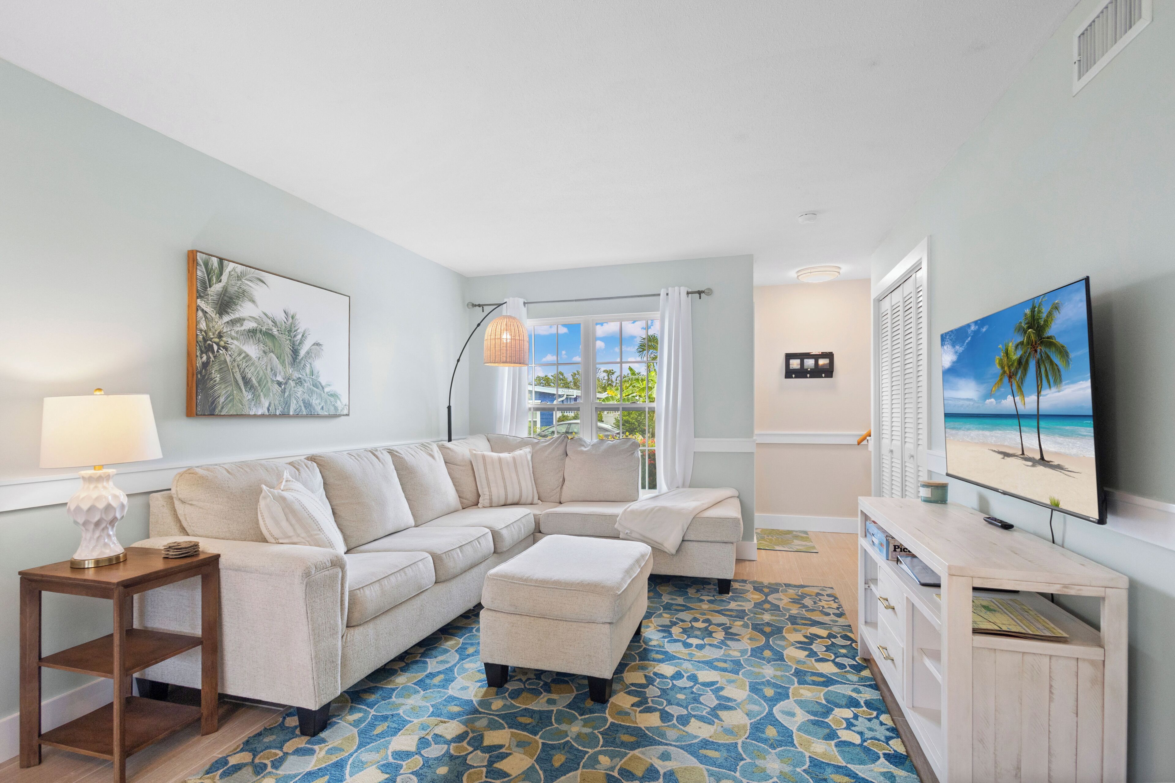 A living room with a sectional sofa, a TV, and artwork on the walls.