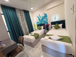 A hotel room with two beds, a desk, a chair, and a large window with curtains. - The Tree Hotel Ravet (Pune)