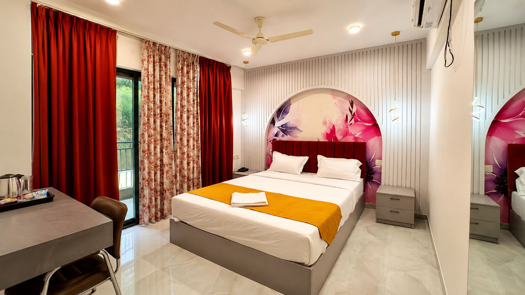A hotel room with a bed, bedside tables, a desk, and a window with curtains.