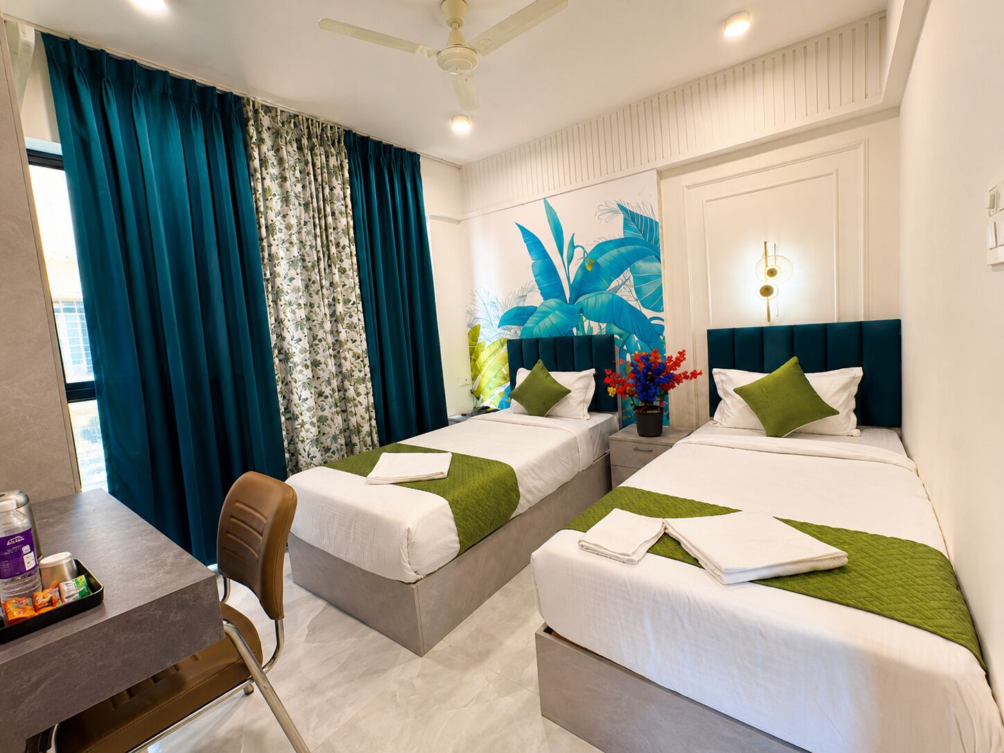 A hotel room with two beds, a desk, and a chair.