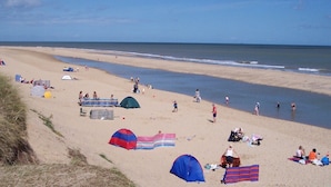 A beach with tents, people, and a clear sky. - These quality bungalows are situated 200mt from Hemsby beaches and all ammenties (Gt Yarmouth)