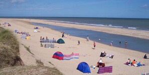 A beach with tents, people, and a clear sky. - These quality bungalows are situated 200mt from Hemsby beaches and all ammenties (Gt Yarmouth)