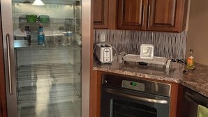 Une cuisine équipée d’un réfrigérateur en acier inoxydable, d’un four encastré et de meubles de rangement en bois.