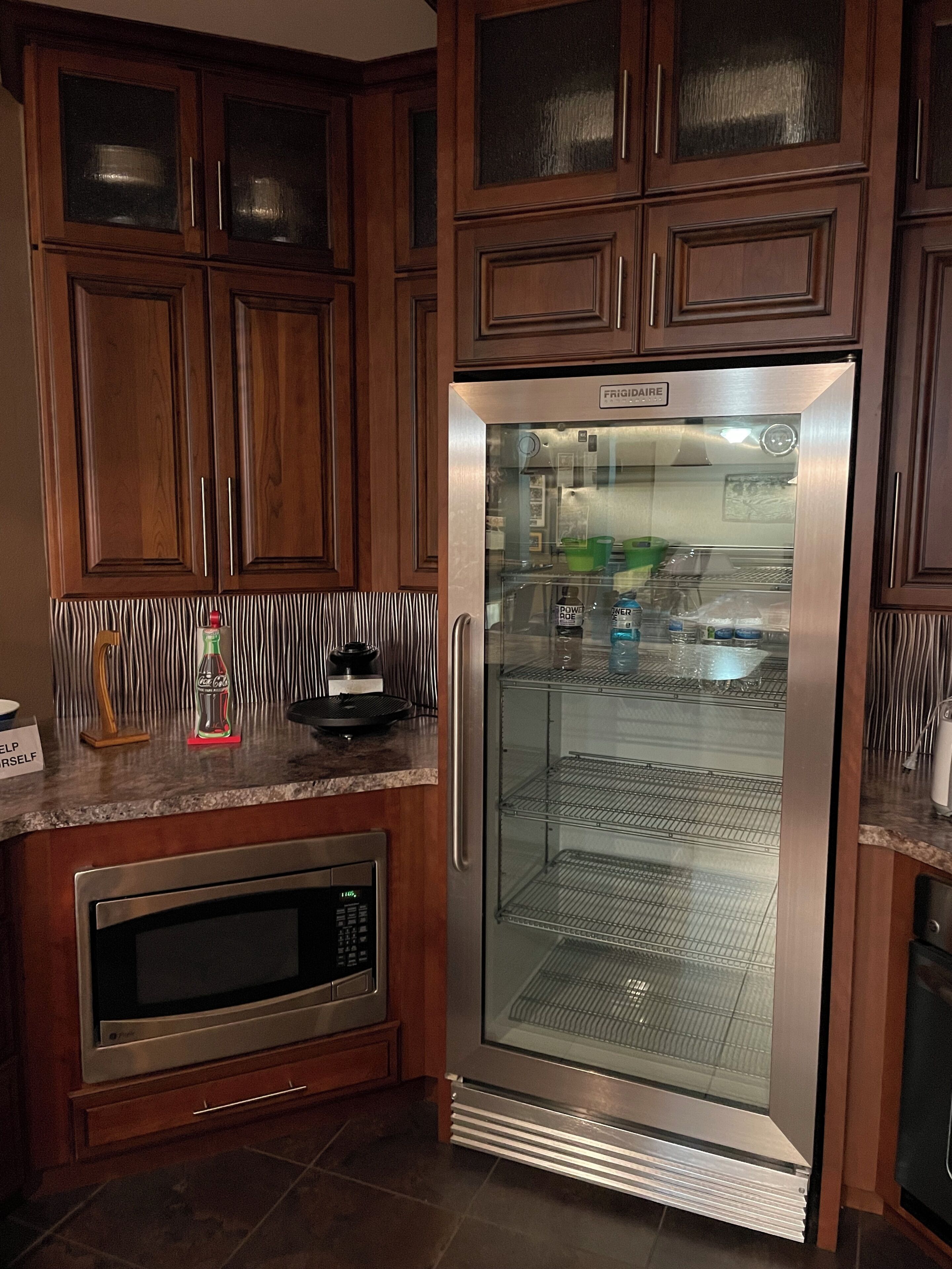 A kitchen with wooden cabinets, a stainless steel refrigerator, and a microwave.
