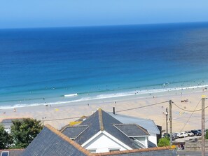 Blick auf die Küste mit Strand, Meer und Gebäuden mit geneigten Dächern.