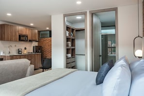 A modern bedroom with a bed, a desk, and a kitchenette. - ENZO Privé | Studios - Modern Executive Suite in Laureles (Medellín)
