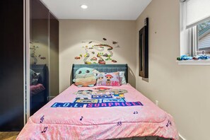 A bedroom with a bed, pillows, a wall decal, and a window with blinds. - The Breeze Stylish Home - Heat Pool (Carrollton)