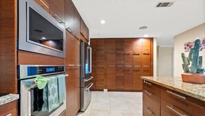 A modern kitchen with stainless steel appliances, wooden cabinets, and a granite countertop.