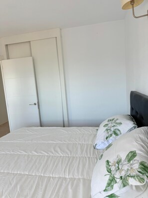 A bedroom with a bed, a closed door, and a wall-mounted lamp. - Sea View Apartment with Terrace, Pool, and Padel Court | Miramar | 45 min from Valencia (Miramar)