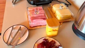 A table with various food items, a bottle of hand sanitizer, and a portable charger. - Pousada Casas Marias Barreirinhas (Barreirinhas)