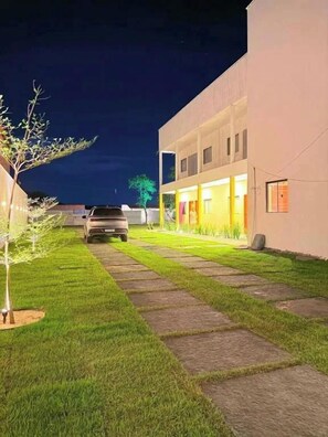 A paved pathway leading to a building with a car parked in front.