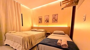 A hotel room with two beds, a nightstand, and wall-mounted artwork. - Pousada Casas Marias Barreirinhas (Barreirinhas)