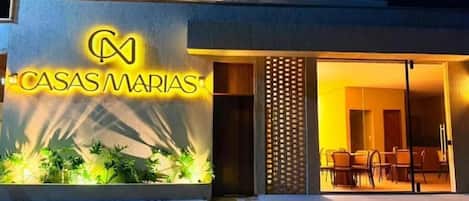 A modern building with a sign reading 'CASAS MARIAS' and an outdoor seating area with chairs.