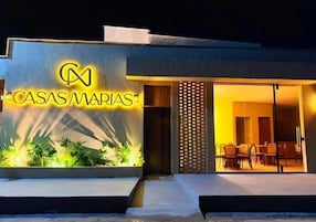 A modern building with a sign reading 'CASAS MARIAS' and an outdoor seating area with chairs.