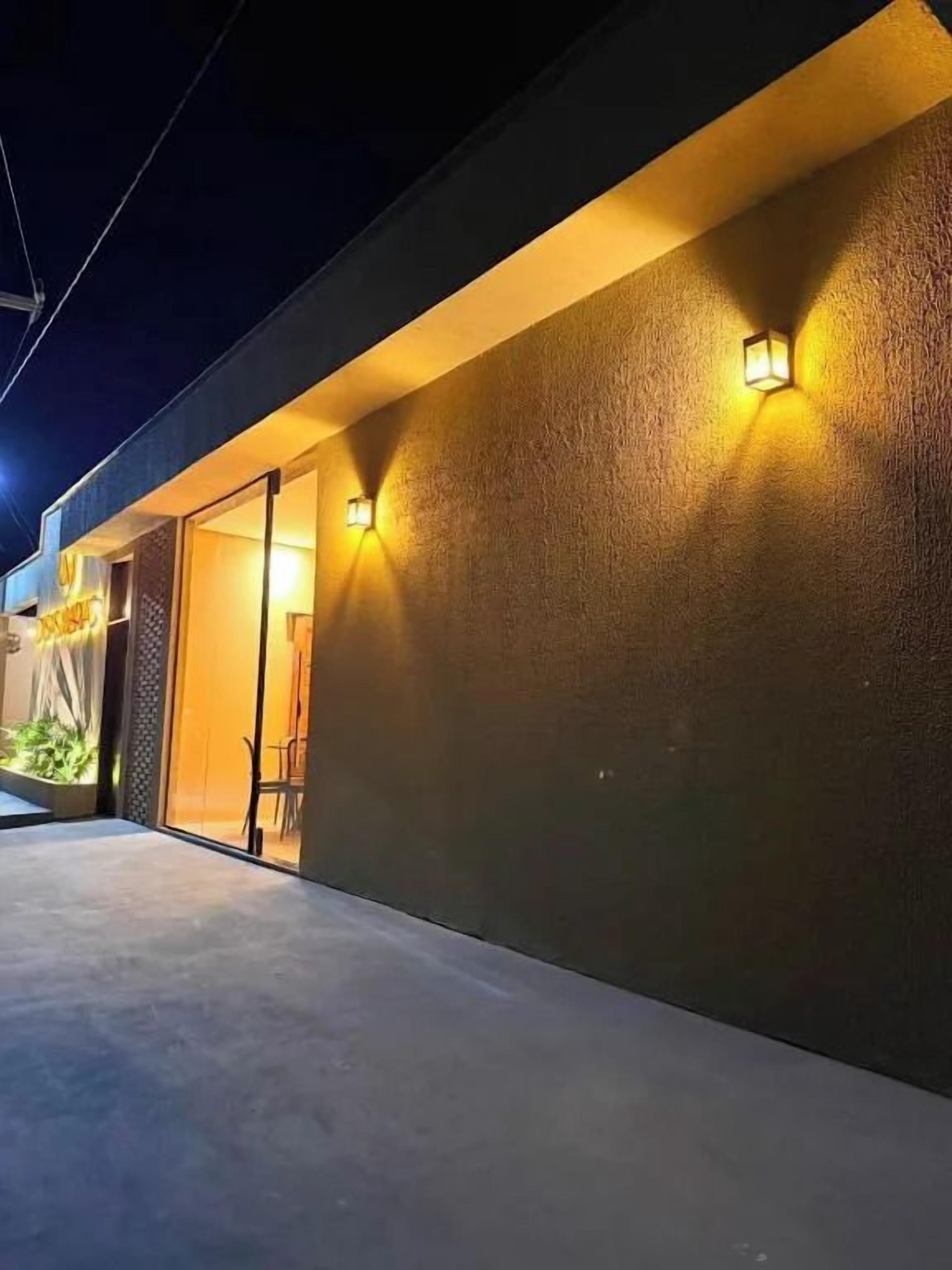 Fachada de prédio com parede texturizada e duas luminárias.