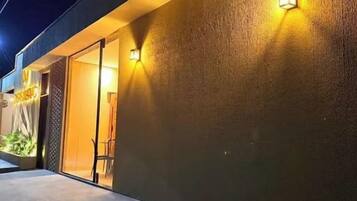 Fachada de prédio com parede texturizada e duas luminárias.