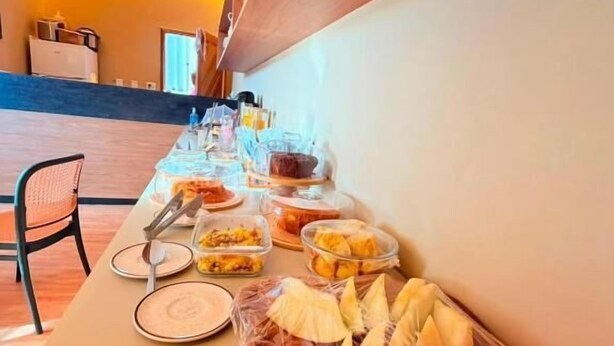 A buffet table with various food items and a chair. - Pousada Casas Marias Barreirinhas (Barreirinhas)