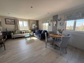 A living room with a sofa, a coffee table, and a dining area with chairs and a table. -  10mins  drive from Terminal 5 & 35 mins train to London Waterloo (Staines-upon-Thames)