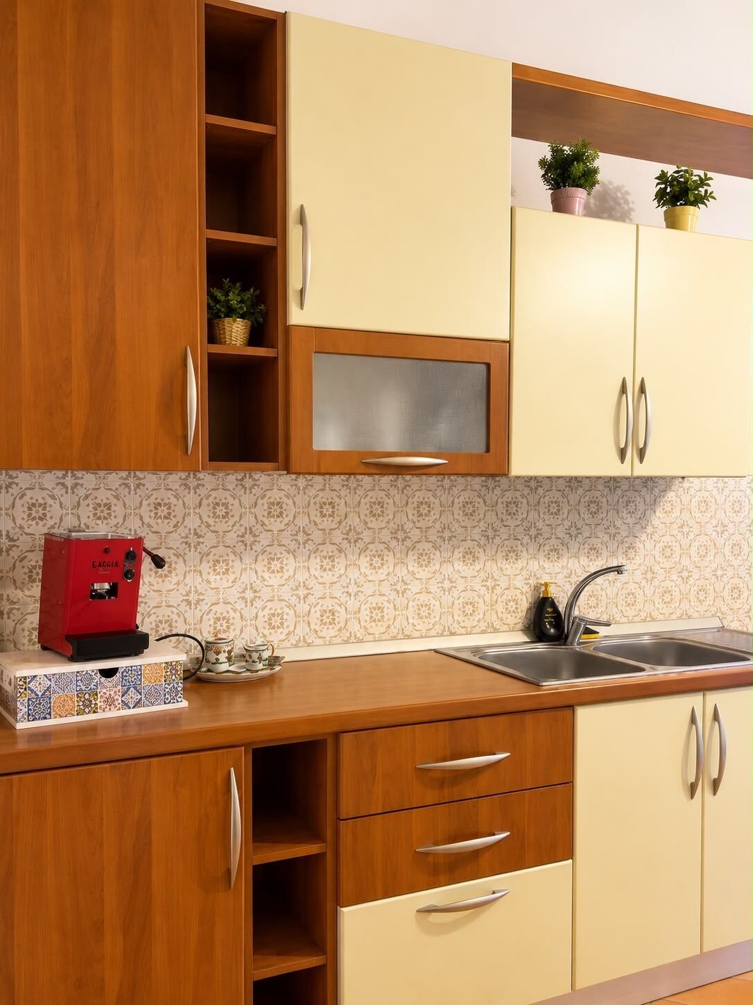 A kitchen with wooden cabinets, a built-in microwave, a coffee machine, and a sink.