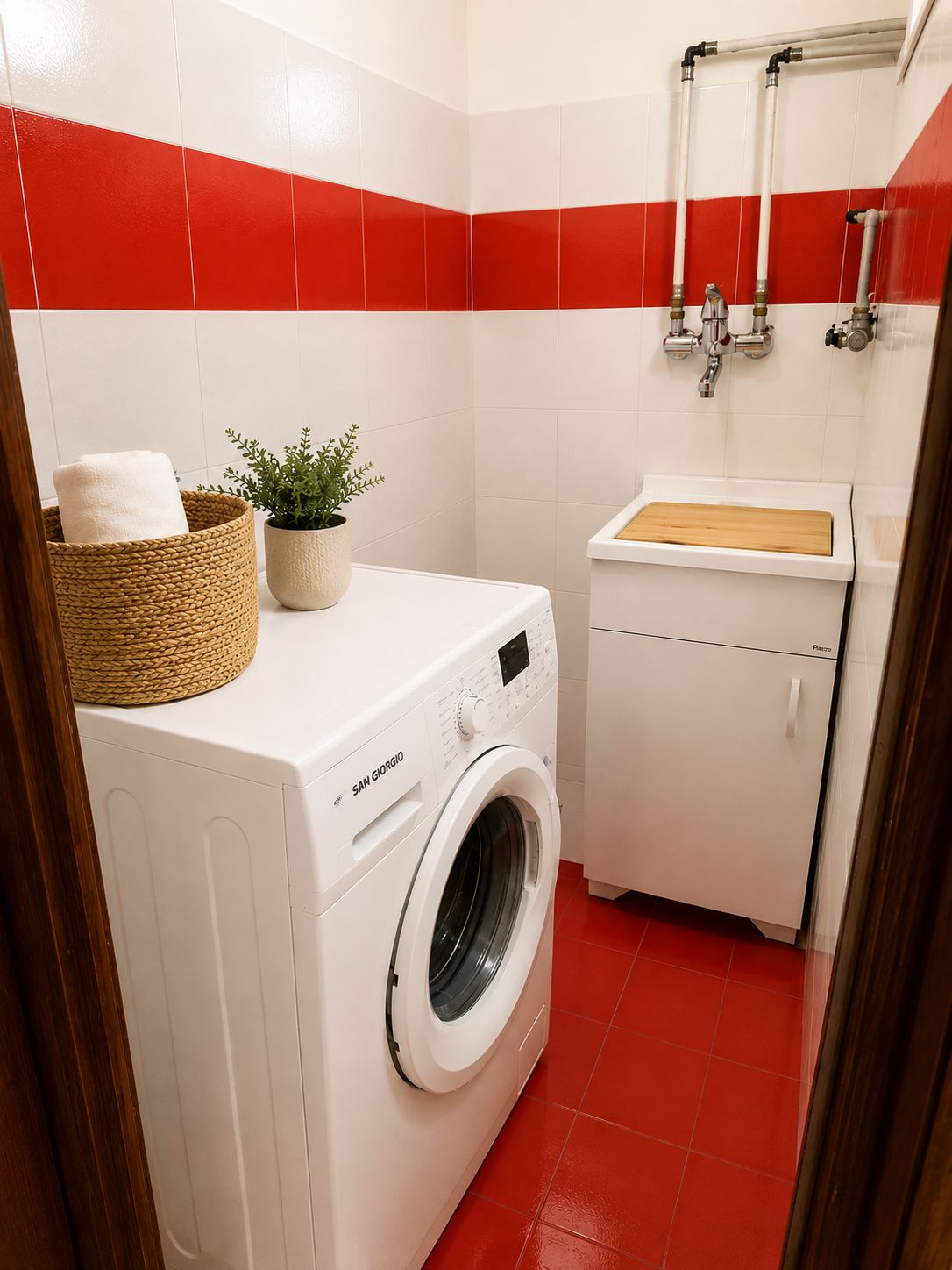 A compact laundry room with a washing machine, a small sink, and a towel rack.