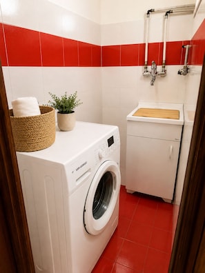 A compact laundry room with a washing machine, a small sink, and a towel rack. - Eolo's House—Sorrento (Sorrento)